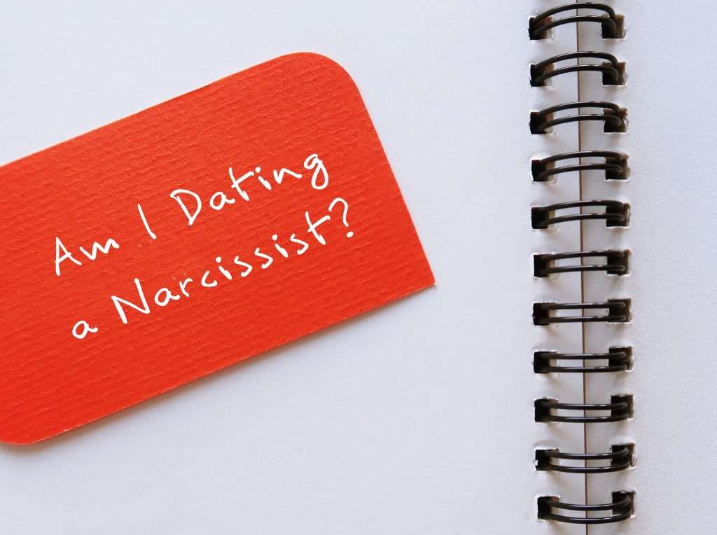 Is It Narcissistic Abuse? Notebook with words "Am I Dating a Narcissist?" illustrating the warning signs of narcissistic abuse and emotional abuse.